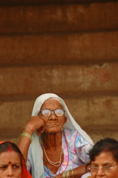 An old woman sits on the steps of a temple, watching the pious euphoria of devotees and holy men alike. (Image courtesy: Tejas Mehta)